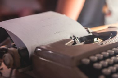 Eski moda daktiloyla beyaz bir kağıda yazı yazma süreci, sıcak oda mum ışığında modern yazar makinesi, el yazısı ve baskı manzarasını kapat 