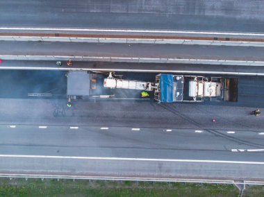 Asphalt paver machine and steam road roller during road construction and repairing works, process of asphalting and paving, workers working on a new road construction site, placing a layer, drone 