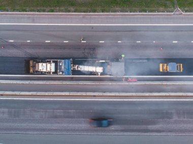 Asphalt paver machine and steam road roller during road construction and repairing works, process of asphalting and paving, workers working on a new road construction site, placing a layer, drone 