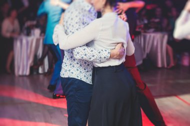 Couples dancing traditional latin argentinian dance milonga in the ballroom hall, tango salsa bachata kizomba lesson in the red lights, dance festival 