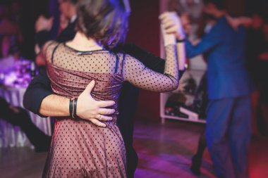 Couples dancing traditional latin argentinian dance milonga in the ballroom hall, tango salsa bachata kizomba lesson in the red lights, dance festival 