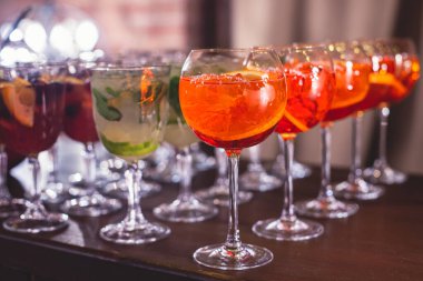 Yemek masasında alkol ayarı, parti, martini, votka, spritz ve dekore edilmiş yemek masasında farklı renkte alkol kokteylleri.