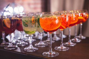 Yemek masasında alkol ayarı, parti, martini, votka, spritz ve dekore edilmiş yemek masasında farklı renkte alkol kokteylleri.