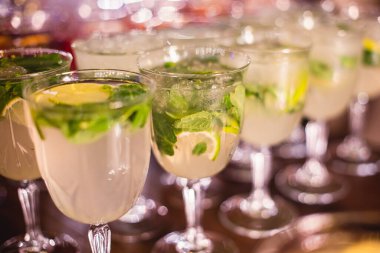Yemek masasında alkol ayarı, parti, martini, votka, spritz ve dekore edilmiş yemek masasında farklı renkte alkol kokteylleri.