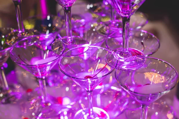 在金字塔里放上含酒精饮料的玻璃杯 盛满并倒入精美的金字塔形的不同颜色的酒精鸡尾酒 派对上还有香槟 — 图库照片