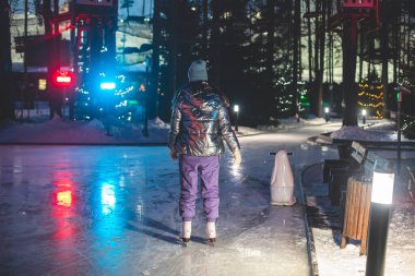 Kız buz pateni sahası etrafında mutlu insanlar, kışın buz pateni konsepti, kış aktiviteleri, noel zamanı, yeni yıl dekorasyonu ve aydınlatma ile