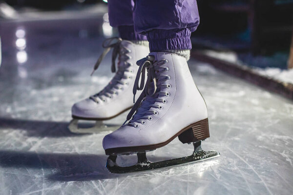 Close up view of new white ice skates boots on rink in motion, girl ice skating on the arena, concept of ice skating in winter, holiday christmas xmas time