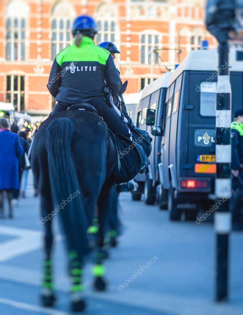 Dutch police squad formation and horseback riding mounted police back view with 