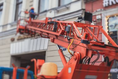 Ön cephe dekorasyonu sırasında hava çalışma platformu aracı, inşaat alanında turuncu teleskopik asansör, şehir sokaklarında çalışan kiralık AWP, yükseklik üzerinde çalışan mühendis