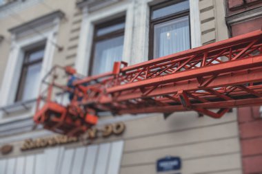 Ön cephe dekorasyonu sırasında hava çalışma platformu aracı, inşaat alanında turuncu teleskopik asansör, şehir sokaklarında çalışan kiralık AWP, yükseklik üzerinde çalışan mühendis