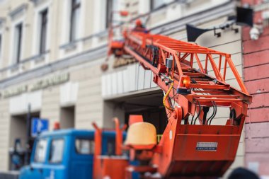 Ön cephe dekorasyonu sırasında hava çalışma platformu aracı, inşaat alanında turuncu teleskopik asansör, şehir sokaklarında çalışan kiralık AWP, yükseklik üzerinde çalışan mühendis