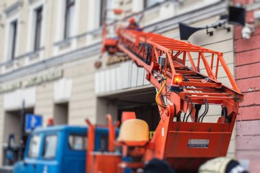 Ön cephe dekorasyonu sırasında hava çalışma platformu aracı, inşaat alanında turuncu teleskopik asansör, şehir sokaklarında çalışan kiralık AWP, yükseklik üzerinde çalışan mühendis