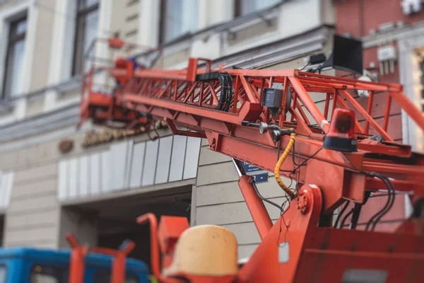 Aerial work platform vehicle during facade decoration, orange telescopic elevator on construction site, rental AWP working in the city streets, engineer working on height