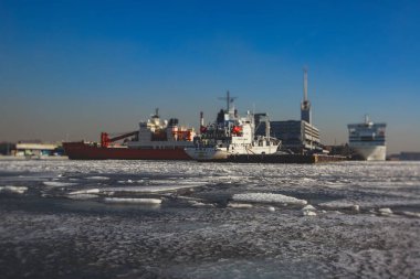 Buzda sıkışmış çok sayıda farklı gemi buzullar, buzkıran ve taşıyıcı gemi ve kış mavisi gökyüzü arasındaki körfezi kırmaya ve terk etmeye çalışıyor.