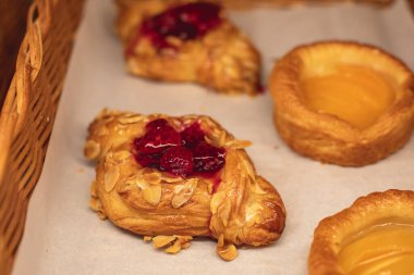 Hamur işleri, farklı fırınlar, kruvasan, İsviçre dürümleri, kek, ekler ve bir sepette ya da tabakta diğerleri, fırında tatlı, yemek servisi ya da kafe ziyafeti masası. 