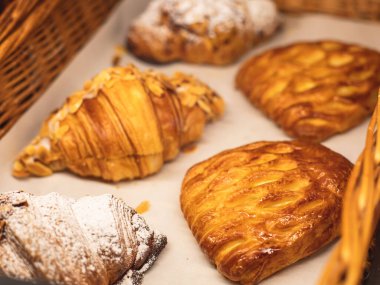 Hamur işleri, farklı fırınlar, kruvasan, İsviçre dürümleri, kek, ekler ve bir sepette ya da tabakta diğerleri, fırında tatlı, yemek servisi ya da kafe ziyafeti masası. 