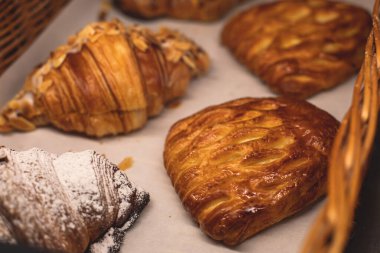 Hamur işleri, farklı fırınlar, kruvasan, İsviçre dürümleri, kek, ekler ve bir sepette ya da tabakta diğerleri, fırında tatlı, yemek servisi ya da kafe ziyafeti masası. 
