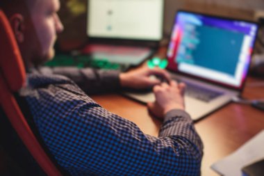 IT geliştirici programcısı evinde, bilgisayarında ve masaüstü monitöründe kodlama programı uygulaması ile çalışıyor ve kodluyor, uzaktan kumanda evden çalışıyor, sıcak akşam resmi