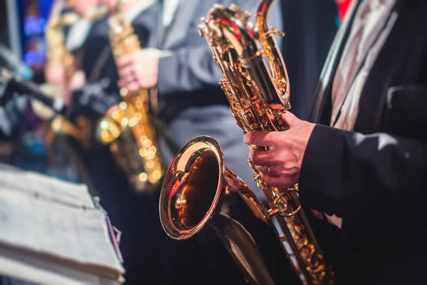 Concert view of a saxophonist, saxophone sax player with vocalist and musical during jazz orchestra performing music on a stage