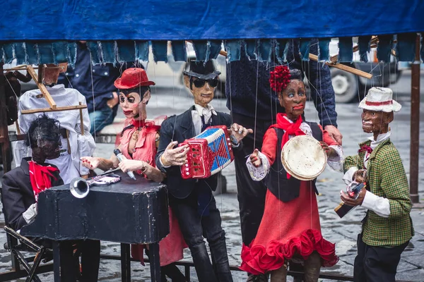 View of street puppet show theatre, with puppeteer puppet master pulling the strings over marionette different dolls