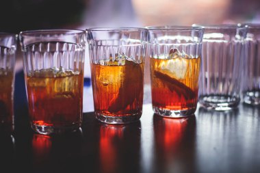 Gece kulübü partisinde barın tezgahında farklı renkte içki kokteylleri, tekila, martinili bardaklar, votka, spritz ve dekore edilmiş yemek masası üzerindeki diğerleri.