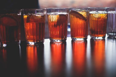 Gece kulübü partisinde barın tezgahında farklı renkte içki kokteylleri, tekila, martinili bardaklar, votka, spritz ve dekore edilmiş yemek masası üzerindeki diğerleri.