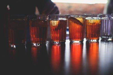 Gece kulübü partisinde barın tezgahında farklı renkte içki kokteylleri, tekila, martinili bardaklar, votka, spritz ve dekore edilmiş yemek masası üzerindeki diğerleri.