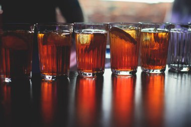 Gece kulübü partisinde barın tezgahında farklı renkte içki kokteylleri, tekila, martinili bardaklar, votka, spritz ve dekore edilmiş yemek masası üzerindeki diğerleri.