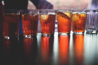 Gece kulübü partisinde barın tezgahında farklı renkte içki kokteylleri, tekila, martinili bardaklar, votka, spritz ve dekore edilmiş yemek masası üzerindeki diğerleri.