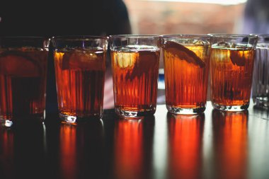 Gece kulübü partisinde barın tezgahında farklı renkte içki kokteylleri, tekila, martinili bardaklar, votka, spritz ve dekore edilmiş yemek masası üzerindeki diğerleri.