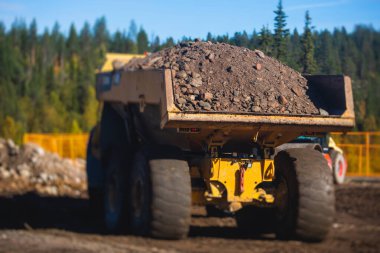 Sarı ağır kazıcı ve çöp kamyonu bahşişçisi kum kazıyor ve yol çalışmaları sırasında çalışıyor, etrafta işçilerin olduğu yeni bir yolun inşaatı sırasında kum boşaltıyor