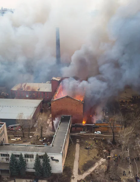 Massive large blaze fire in the city, aerial drone top view brick factory building on fire, hell major fire explosion flame blast,  with firefighters team, arson, burning damage destruction