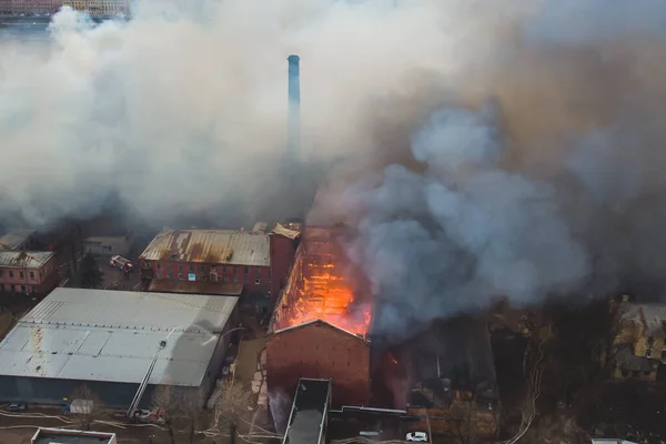 Massive large blaze fire in the city, aerial drone top view brick factory building on fire, hell major fire explosion flame blast,  with firefighters team, arson, burning damage destruction