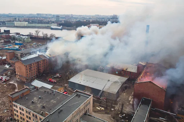 Massive large blaze fire in the city, aerial drone top view brick factory building on fire, hell major fire explosion flame blast,  with firefighters team, arson, burning damage destruction