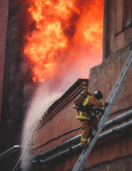 Firefighters put out large massive fire blaze, group of fire men in uniform during fire fighting operation in the city streets, firefighters with fire engine truck fighting vehicle