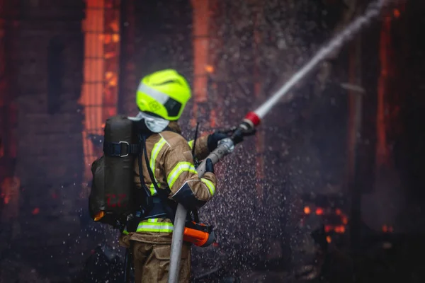 Firefighters put out large massive fire blaze, group of fire men in uniform during fire fighting operation in the city streets, firefighters with fire engine truck fighting vehicle