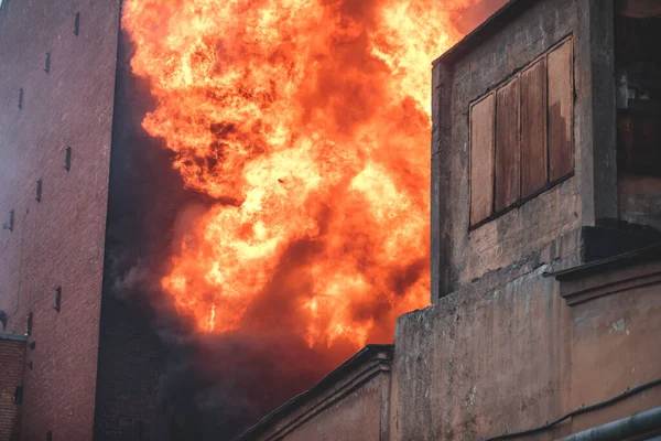 Massive large blaze fire in the city, brick factory building on fire, hell major fire explosion flame blast,  with firefighters team firemen on duty, arson, burning house destruction