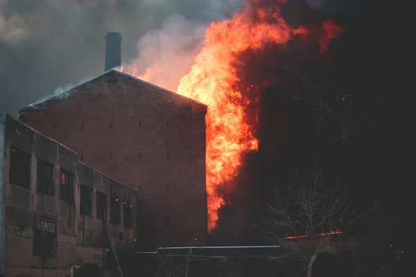 Massive large blaze fire in the city, brick factory building on fire, hell major fire explosion flame blast,  with firefighters team firemen on duty, arson, burning house destruction