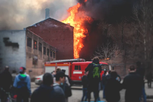 Massive large blaze fire in the city, brick factory building on fire, hell major fire explosion flame blast,  with firefighters team firemen on duty, arson, burning house destruction