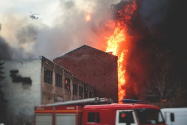 Massive large blaze fire in the city, brick factory building on fire, hell major fire explosion flame blast,  with firefighters team firemen on duty, arson, burning house destruction