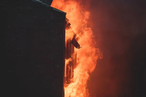 Massive large blaze fire in the city, brick factory building on fire, hell major fire explosion flame blast,  with firefighters team firemen on duty, arson, burning house destruction