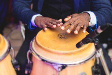 Latin Kübalı bando arka planda, baterist bakış açısıyla, caz rock konserinde konga davul setinin sahne aldığı bir sahnede bongo davulcusu perküsyoncusu. 