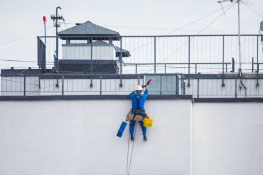 Yüksek binaların camlarını temizleyen profesyonel tırmanma halatı işçisi, endüstriyel dağcılar modern bir binanın cam cephesini yıkıyorlar, yüksek yerlerde çalışmak riskli. 