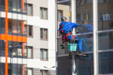 Yüksek binaların camlarını temizleyen profesyonel tırmanma halatı işçisi, endüstriyel dağcılar modern bir binanın cam cephesini yıkıyorlar, yüksek yerlerde çalışmak riskli. 