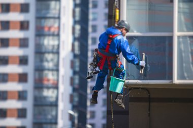 Yüksek binaların camlarını temizleyen profesyonel tırmanma halatı işçisi, endüstriyel dağcılar modern bir binanın cam cephesini yıkıyorlar, yüksek yerlerde çalışmak riskli. 
