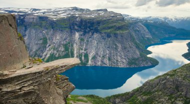 Yürüyüş yer - trolltunga, troller dil, bir turist ile kaya skjegedall ve göl ringedalsvatnet ve dağ panoramik manzara epik görünümü, Norveç ünlü Norveçli canlı bir resmini