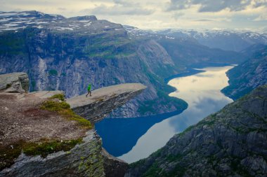 Yürüyüş yer - trolltunga, troller dil, bir turist ile kaya skjegedall ve göl ringedalsvatnet ve dağ panoramik manzara epik görünümü, Norveç ünlü Norveçli canlı bir resmini