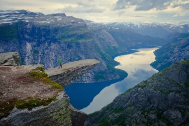 Yürüyüş yer - trolltunga, troller dil, bir turist ile kaya skjegedall ve göl ringedalsvatnet ve dağ panoramik manzara epik görünümü, Norveç ünlü Norveçli canlı bir resmini