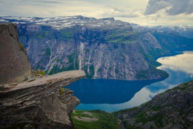 Yürüyüş yer - trolltunga, troller dil, bir turist ile kaya skjegedall ve göl ringedalsvatnet ve dağ panoramik manzara epik görünümü, Norveç ünlü Norveçli canlı bir resmini