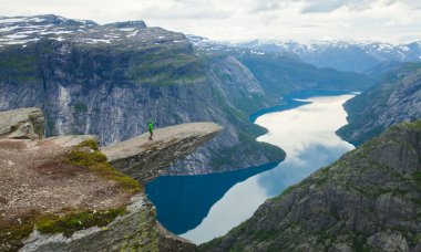 Yürüyüş yer - trolltunga, troller dil, bir turist ile kaya skjegedall ve göl ringedalsvatnet ve dağ panoramik manzara epik görünümü, Norveç ünlü Norveçli canlı bir resmini